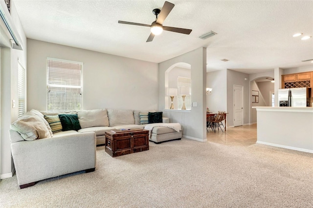 living room featuring a textured ceiling, ceiling fan, and light carpet