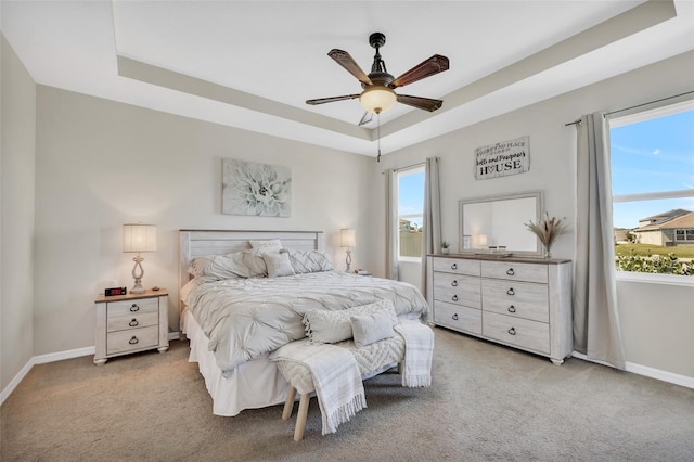 carpeted bedroom featuring ceiling fan and a tray ceiling