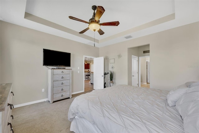 carpeted bedroom with ceiling fan and a tray ceiling