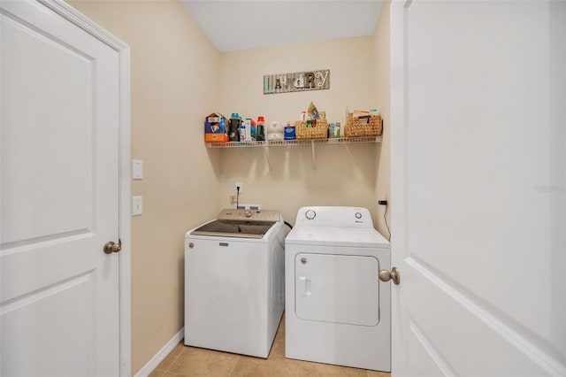 clothes washing area featuring light tile flooring and washer and dryer