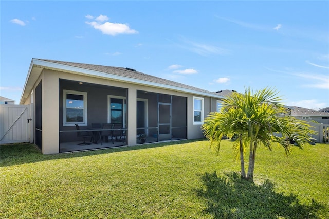 back of property with a patio area, a sunroom, and a lawn