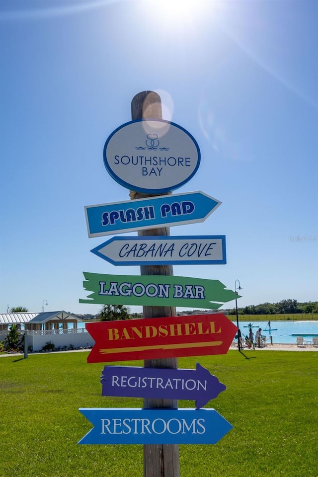 community sign featuring a water view and a lawn