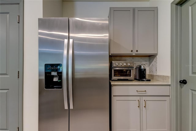 kitchen with backsplash and stainless steel refrigerator with ice dispenser