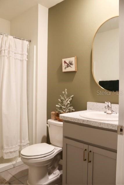 bathroom featuring toilet, tile patterned flooring, walk in shower, and vanity