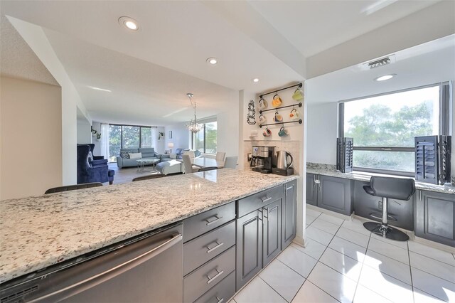 kitchen featuring a fireplace, gray cabinets, light stone counters, dishwasher, and light tile floors