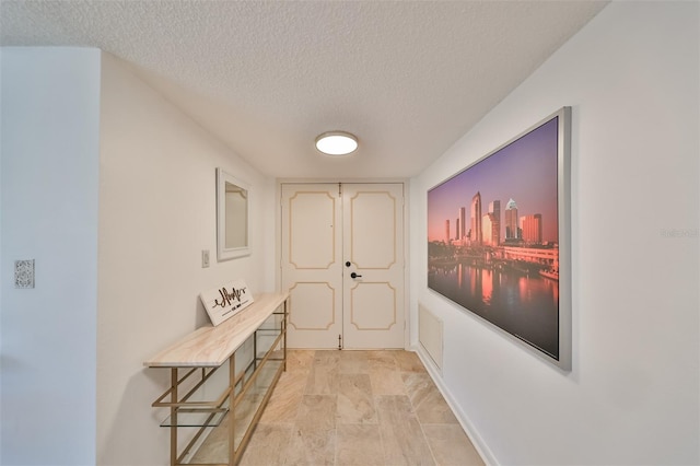 corridor with a textured ceiling and light tile floors