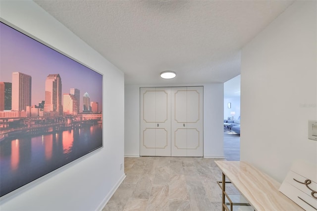 hallway featuring a textured ceiling and light tile floors