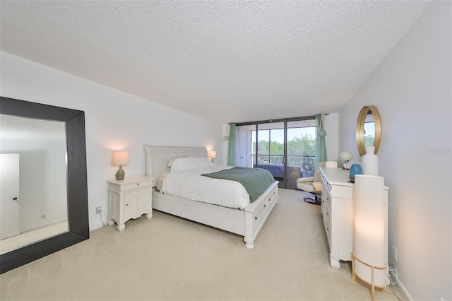 bedroom featuring access to outside, a textured ceiling, and light colored carpet