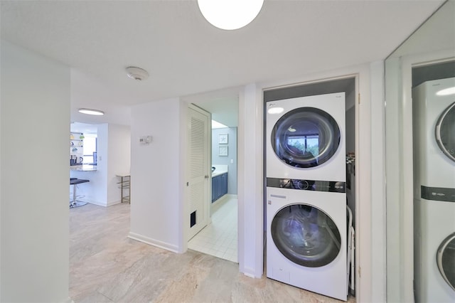 laundry area featuring stacked washer / dryer and light tile floors