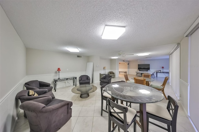 tiled dining room with ceiling fan and a textured ceiling