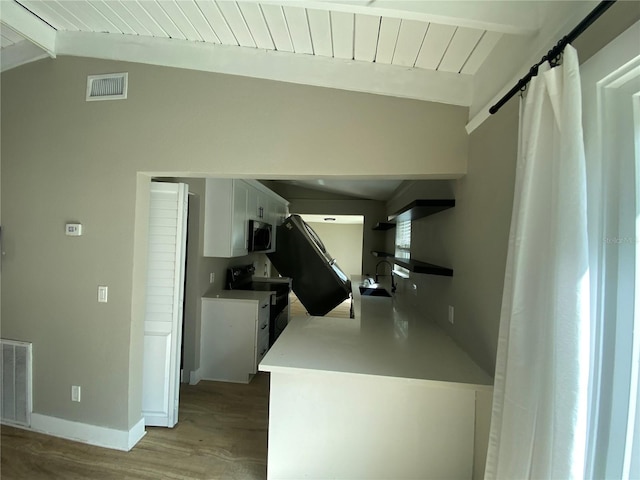 kitchen with white cabinetry, a barn door, vaulted ceiling with beams, black electric range, and light hardwood / wood-style floors