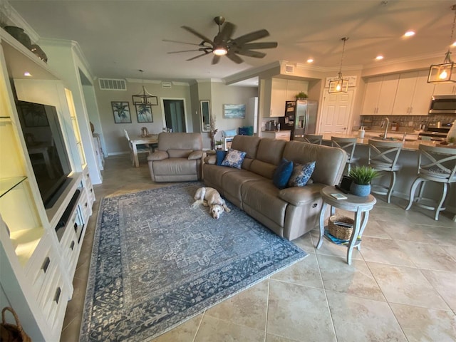 tiled living room with ceiling fan, ornamental molding, and sink