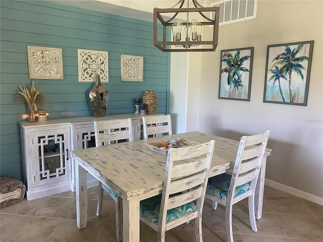 dining space with a notable chandelier, wood walls, and tile patterned flooring