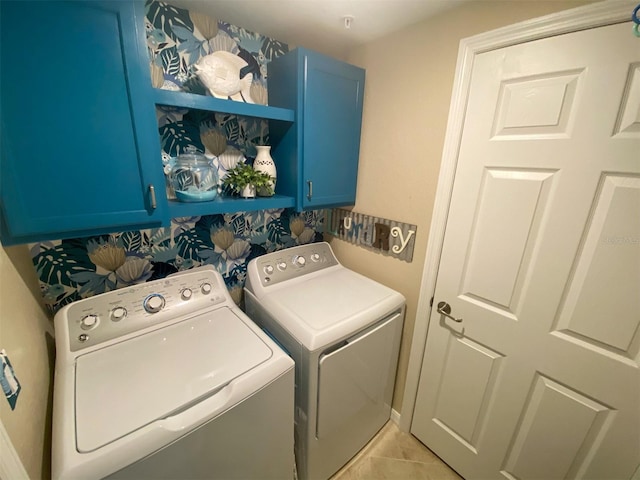 washroom featuring cabinets, washing machine and clothes dryer, and light tile patterned floors