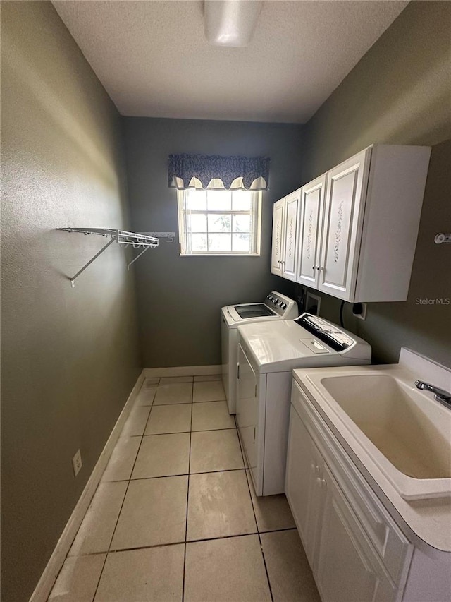 clothes washing area with cabinets, light tile flooring, washer hookup, washer and dryer, and sink