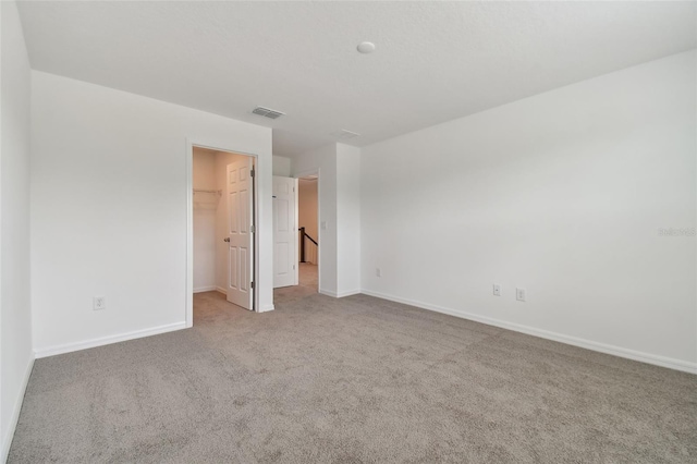 unfurnished bedroom featuring a walk in closet, light colored carpet, and a closet