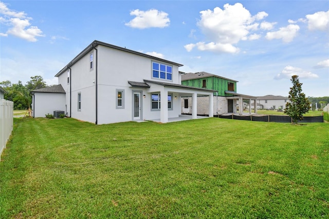 rear view of house featuring cooling unit, a yard, and a patio area