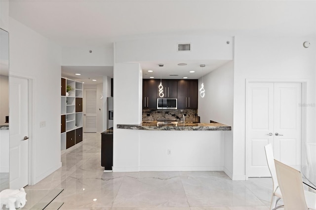 kitchen featuring backsplash, decorative light fixtures, appliances with stainless steel finishes, stone countertops, and dark brown cabinets