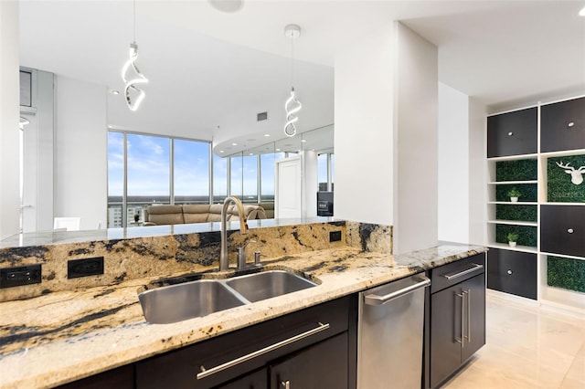 kitchen with stainless steel dishwasher, decorative light fixtures, light stone counters, and sink