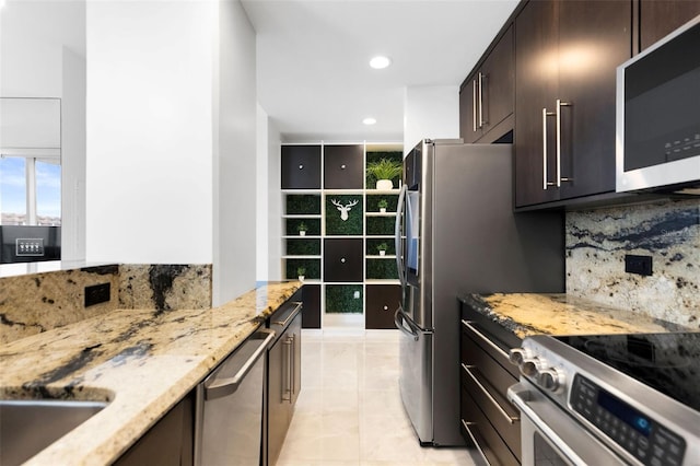 kitchen featuring dark brown cabinetry, appliances with stainless steel finishes, decorative backsplash, and light stone countertops