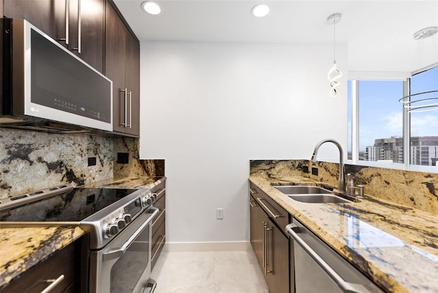 kitchen with tasteful backsplash, decorative light fixtures, stainless steel appliances, light stone counters, and sink