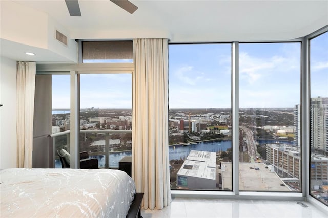 tiled bedroom with ceiling fan, expansive windows, and a water view