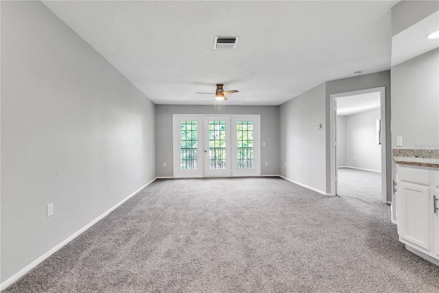 interior space featuring a textured ceiling, ceiling fan, and light carpet