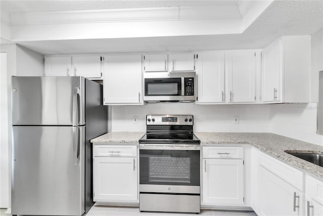 kitchen featuring tasteful backsplash, appliances with stainless steel finishes, white cabinets, and light stone counters