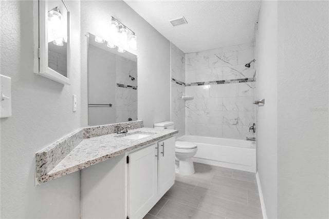 full bathroom with tile flooring, tiled shower / bath combo, a textured ceiling, oversized vanity, and toilet