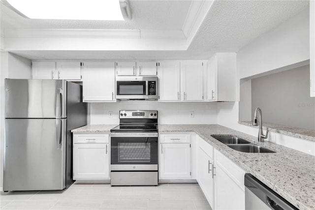 kitchen with light stone counters, appliances with stainless steel finishes, sink, white cabinetry, and ornamental molding