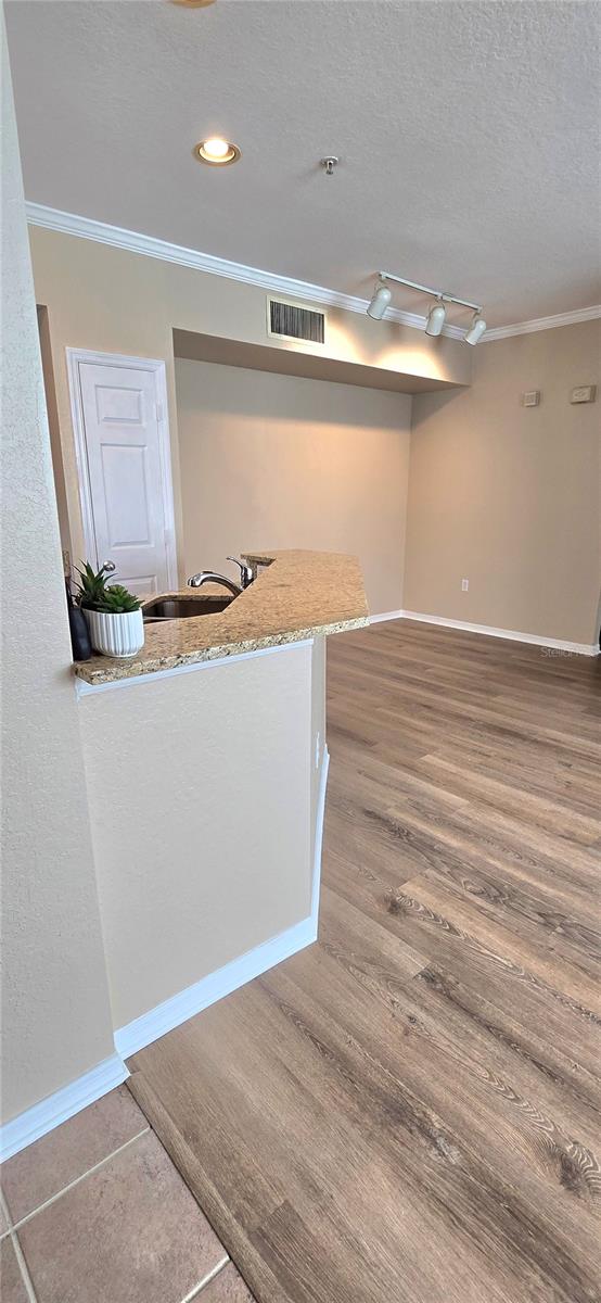 interior space featuring rail lighting, a textured ceiling, crown molding, hardwood / wood-style flooring, and sink