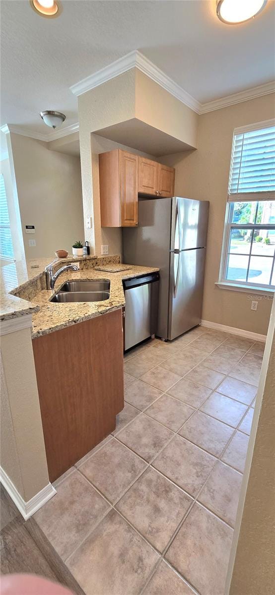 kitchen featuring appliances with stainless steel finishes, light stone countertops, kitchen peninsula, and sink