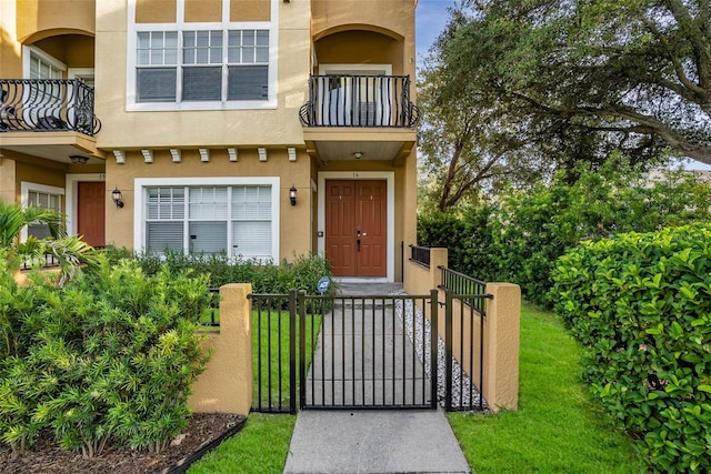 entrance to property with a balcony and a lawn