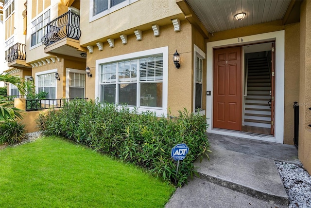 doorway to property featuring a balcony and a lawn