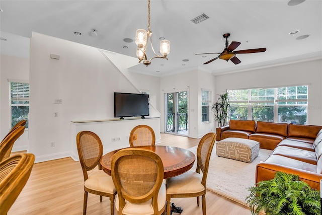 dining room featuring ceiling fan with notable chandelier, a healthy amount of sunlight, light hardwood / wood-style flooring, and ornamental molding