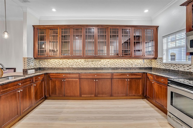 kitchen featuring stainless steel appliances, tasteful backsplash, dark stone counters, pendant lighting, and light wood-type flooring