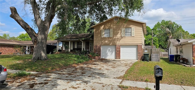 split level home with a front lawn, fence, concrete driveway, an attached garage, and brick siding