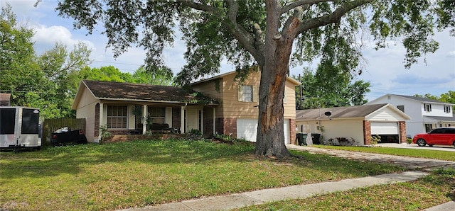 split level home with a garage, a front yard, concrete driveway, and brick siding