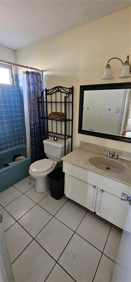 bathroom with tile patterned flooring, shower / tub combo, toilet, and vanity