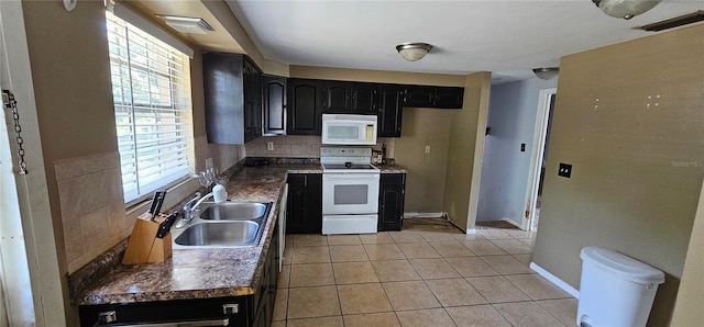 kitchen with dark cabinets, white appliances, decorative backsplash, and a sink