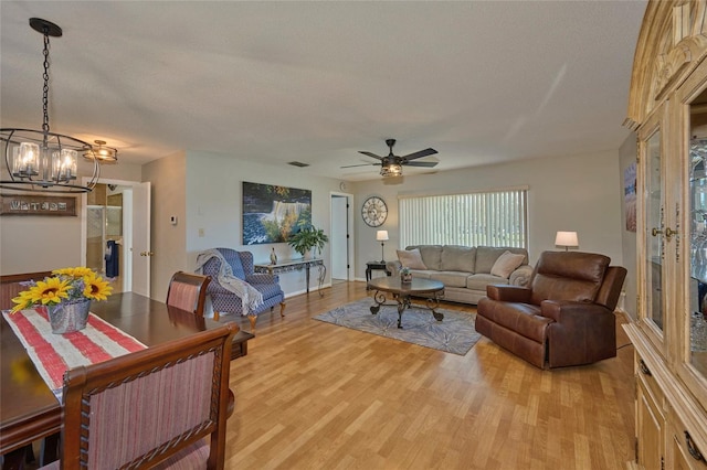 living room featuring light hardwood / wood-style floors and ceiling fan with notable chandelier