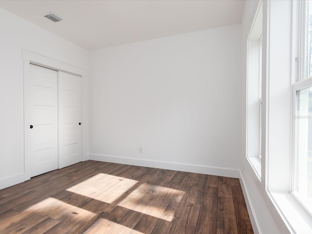 unfurnished room featuring a wealth of natural light and dark hardwood / wood-style flooring