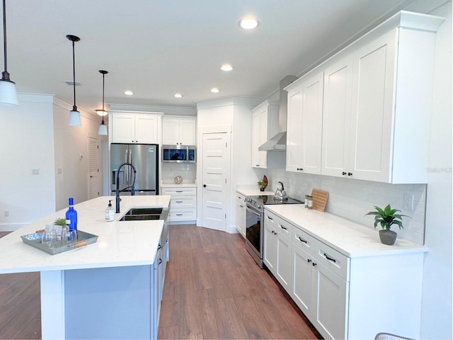 kitchen with tasteful backsplash, a center island with sink, pendant lighting, white cabinets, and appliances with stainless steel finishes