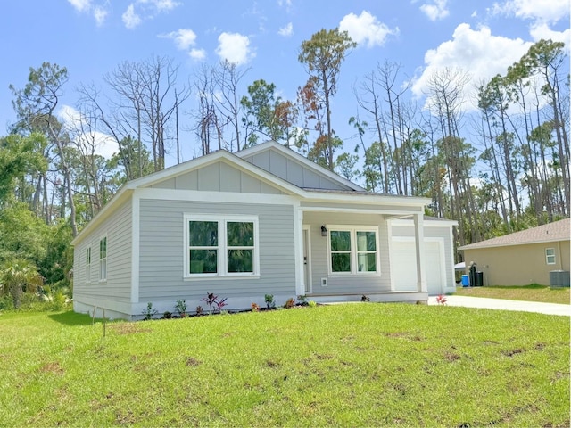 view of front of property featuring a garage, a front yard, and central AC unit