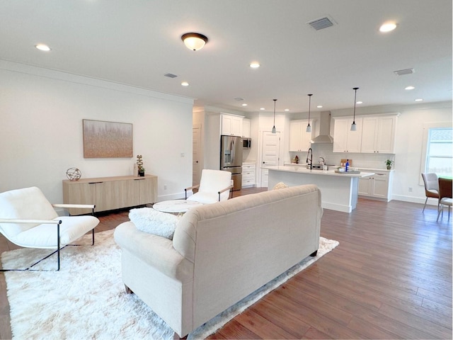 living room featuring crown molding, hardwood / wood-style flooring, and sink