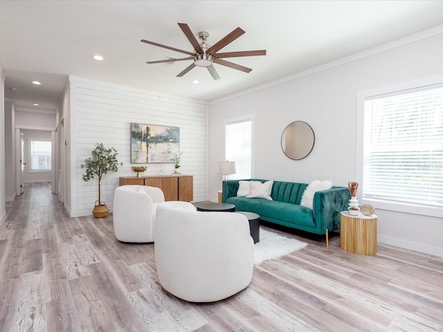 living room with ornamental molding, ceiling fan, and light wood-type flooring