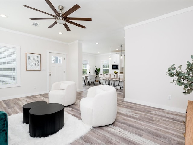 living room with light hardwood / wood-style flooring, ceiling fan, and ornamental molding