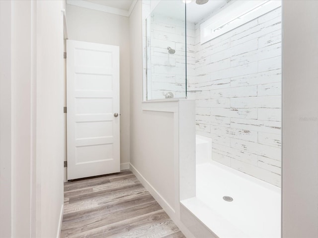 bathroom with hardwood / wood-style flooring, crown molding, and a shower