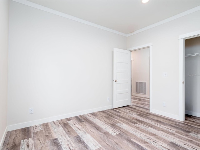 unfurnished bedroom with ornamental molding, a closet, and hardwood / wood-style flooring