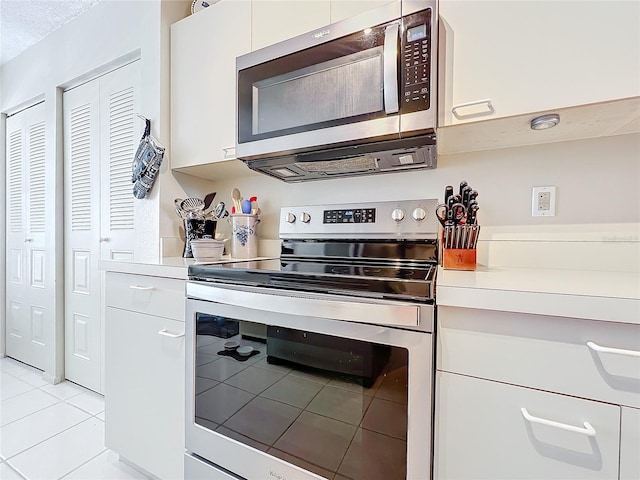 kitchen featuring white cabinets, appliances with stainless steel finishes, and light tile floors